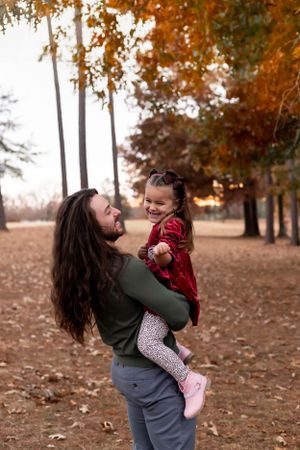 Candid moment of parent and child playing outdoors in autumn setting.