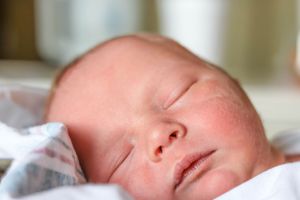 Close-up of a sleeping newborn baby's face showing peaceful expression.