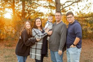 Family group poses together in outdoor setting during golden sunset hour.