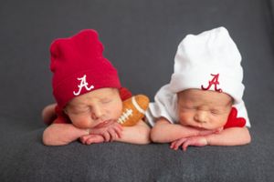 Twin babies with Alabama football beanies posed with small football between them.