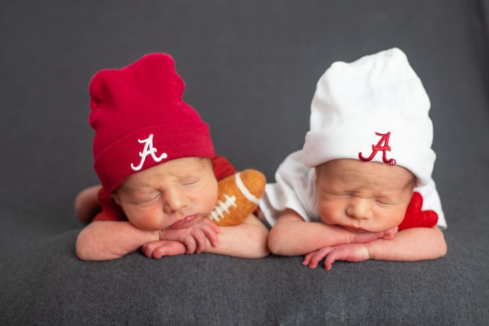 Twin babies with Alabama football beanies posed with small football between them.