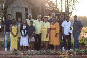 Large family group poses together in front of rustic building with tulip garden.