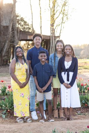 Group poses together in spring garden with blooming tulips at sunset.