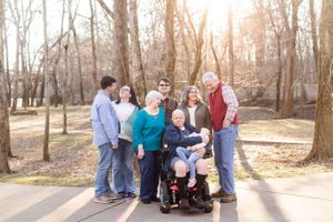 Extended family gathers together on park path during golden hour photo session.