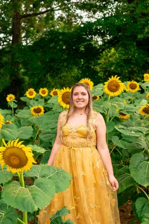 Beautiful yellow dress creates stunning contrast against field of bright sunflowers.