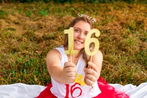 Sweet sixteen celebration with gold number balloons against natural outdoor setting.