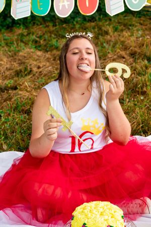 Celebration moment with red tulle skirt and decorated banner in outdoor setting.