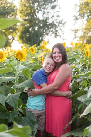 Mother and child share embrace in beautiful sunflower field during summer.