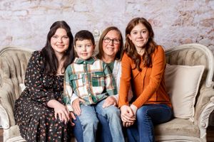 Group portrait on vintage sofa against textured wall background.