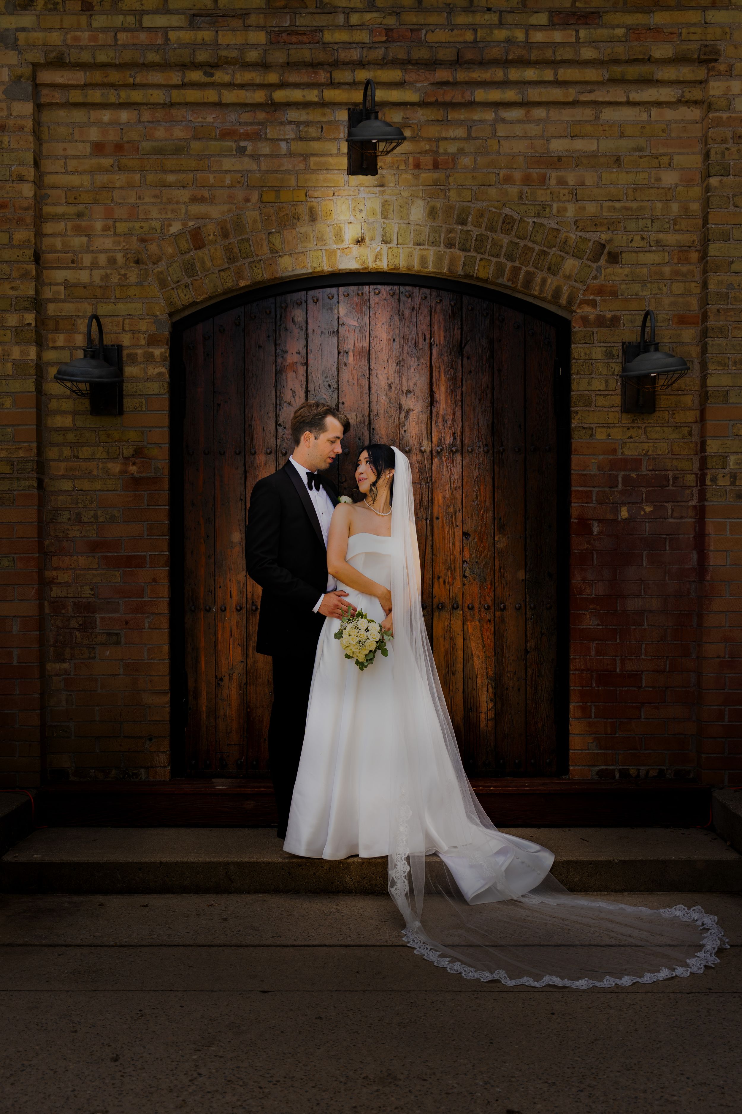 Elegant wedding photography sequence against brick wall with vintage wooden doors.