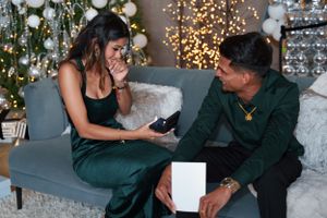 Romantic indoor engagement photoshoot with Christmas lights and decorations.