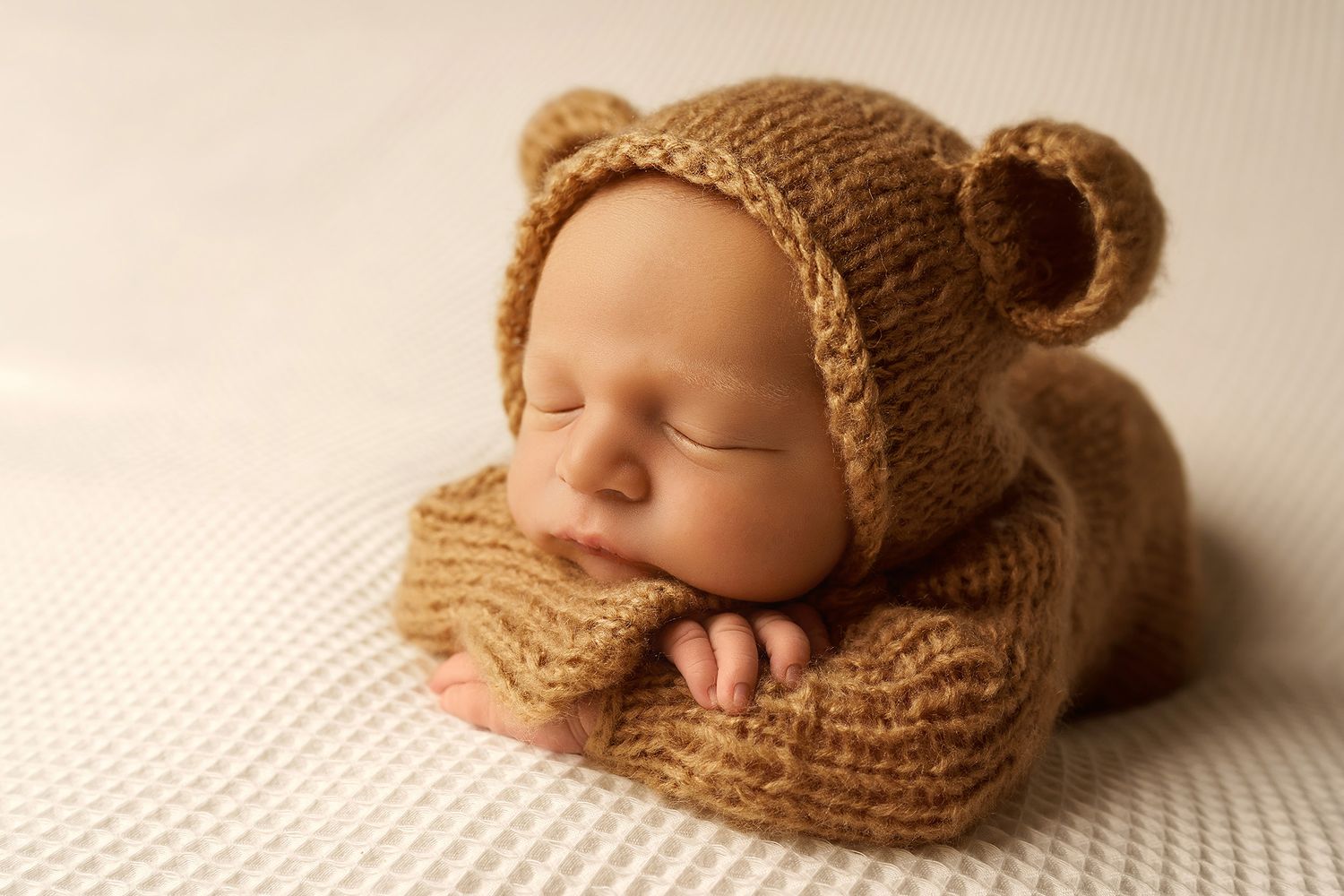 Newborn in brown soft onesie with teddy bear matching hat