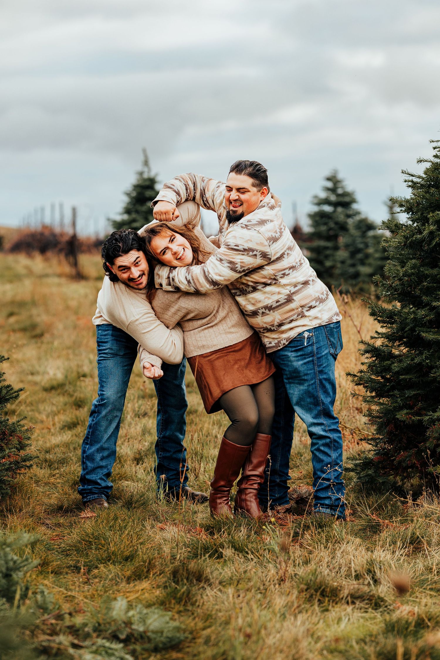 Two brothers playfully tease their sister during a family photo session at a christmas tree farm