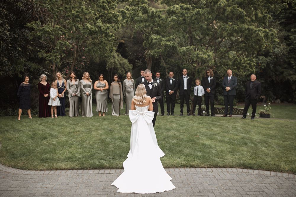 A wedding party lineup on a manicured lawn with the couple in the center.