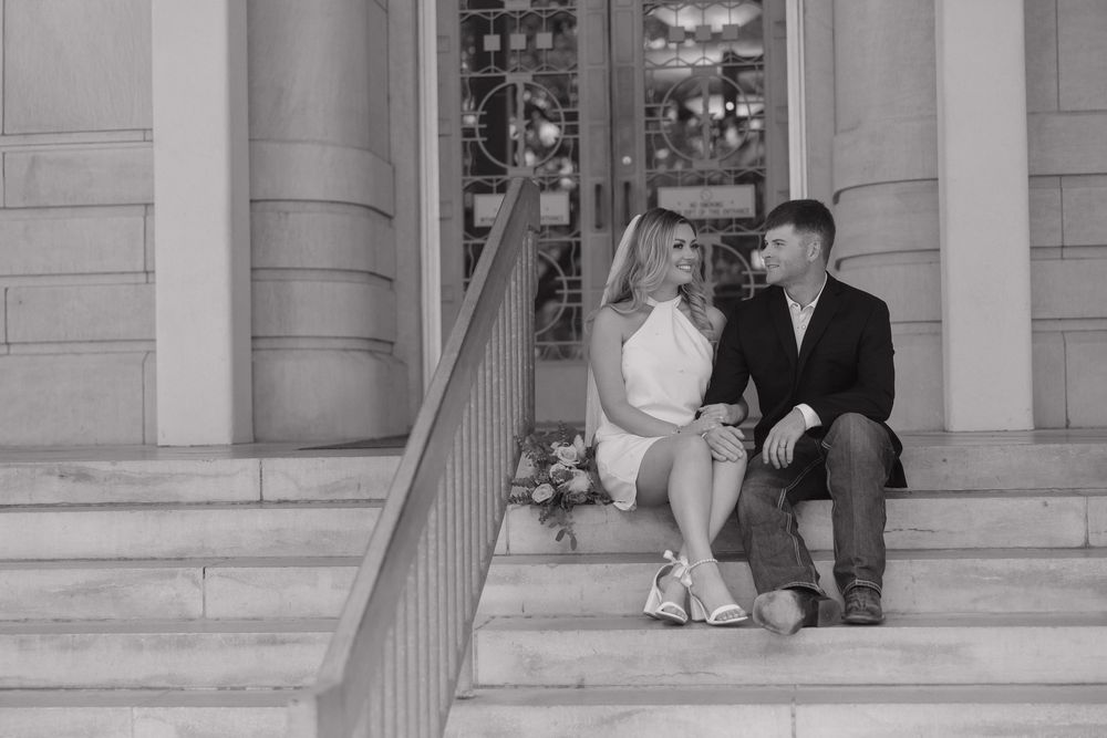 Vintage black and white photo of a couple descending ornate stone steps at a formal building entrance.