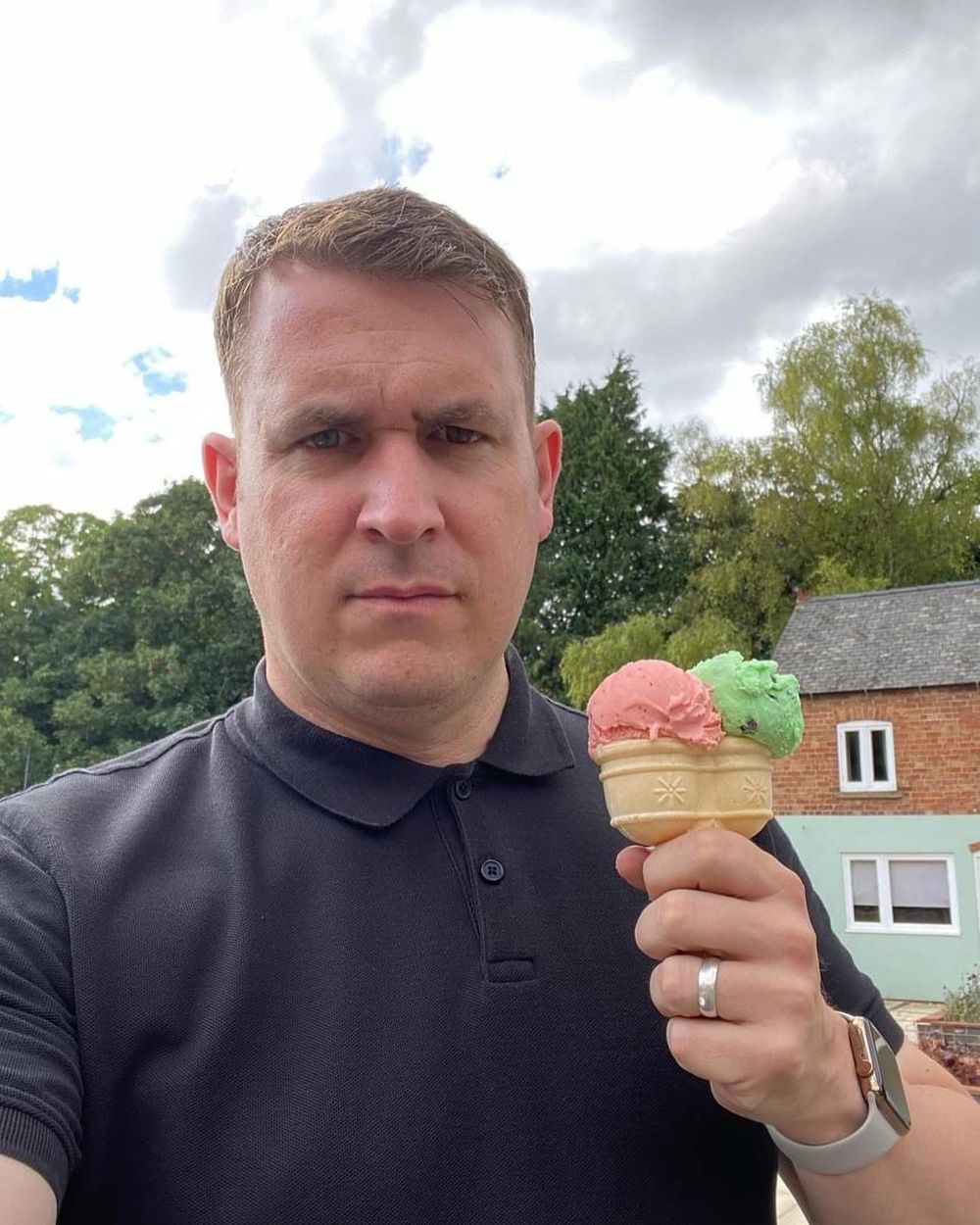 Someone enjoying two scoops of colorful ice cream outdoors on a cloudy day.