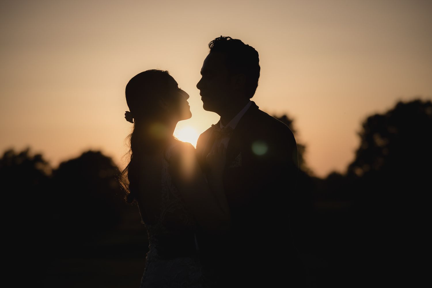 Father of the bride looks lovingly into his daughters eyes whilst being watched by a bridesmaid at a wedding in Cheshire