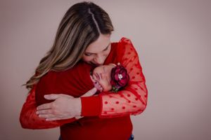 Mother cuddles newborn in this silky smooth colorful posed portrait