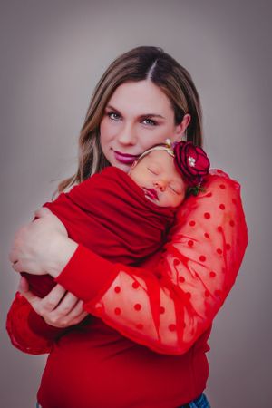 Mother cuddles newborn in this silky smooth colorful posed portrait