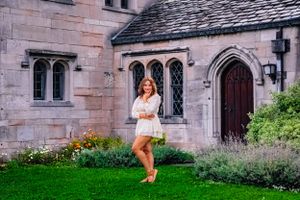 High school senior posing confidently outdoors with a natural smile, dressed in stylish attire, with soft golden sunlight highlighting their