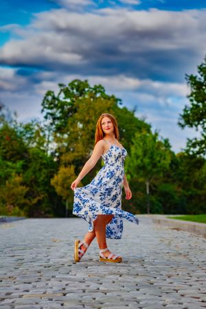 High school senior posing confidently outdoors with a natural smile, dressed in stylish attire, with soft golden sunlight highlighting their