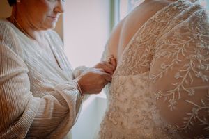 mother of bride zips up her daughters bridal gown