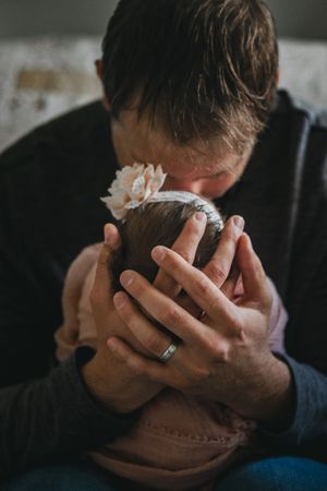 a new dad cradles his baby's head close to his heart