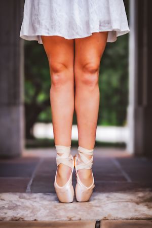 Senior ballerina posing on pointe outdoors with soft natural light and warm colors.