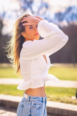 High school senior posing confidently outdoors with a natural smile, dressed in stylish attire, with soft golden sunlight highlighting their