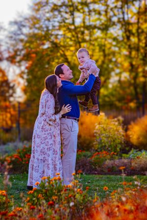 Family posing naturally outdoors with a natural smile, dressed in stylish attire, with soft golden sunlight highlighting their