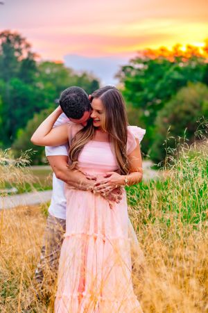 A couple shares a loving hug in front of a gorgeous sunset
