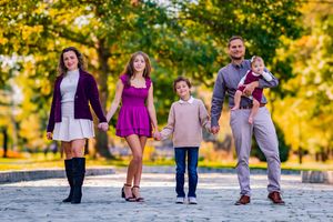Family posing confidently outdoors with a natural smile, dressed in stylish attire, with soft golden sunlight highlighting their