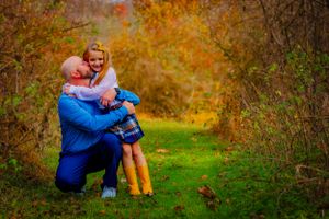 a father hugs his daughter amidst a forest of vivid hues