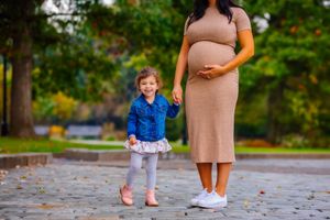 maternity picture of girl holding mom's hand