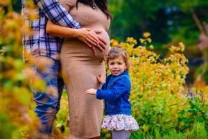 adorable girl clinging to parents. focus on pregnant mom's belly