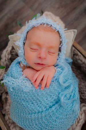 newborn wrapped in soft blue blanket during newborn session