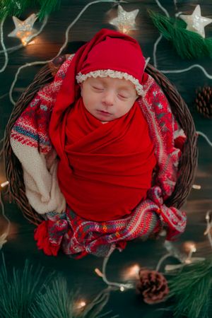 Newborn snuggling in christmas decor, indoors, creamy bold colors