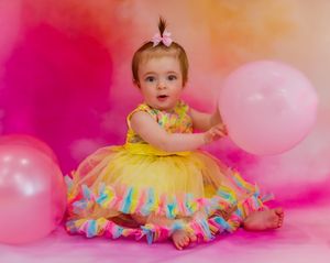 adorable first birthday picture of a baby holding a pink balloon