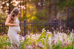 Outdoor maternity session with rich colors and a peaceful, glowing sunset behind the expecting mother.