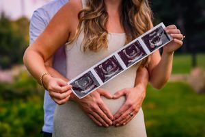 Pregnant woman posing with partner during a maternity session with warm, picture-perfect tones