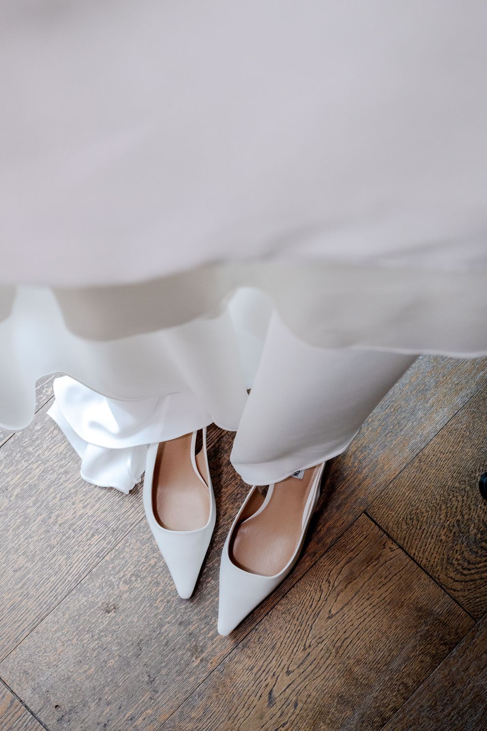 A series of photos showing white wedding dress fabric flowing over pale pink ballet flats on a rustic wooden floor.