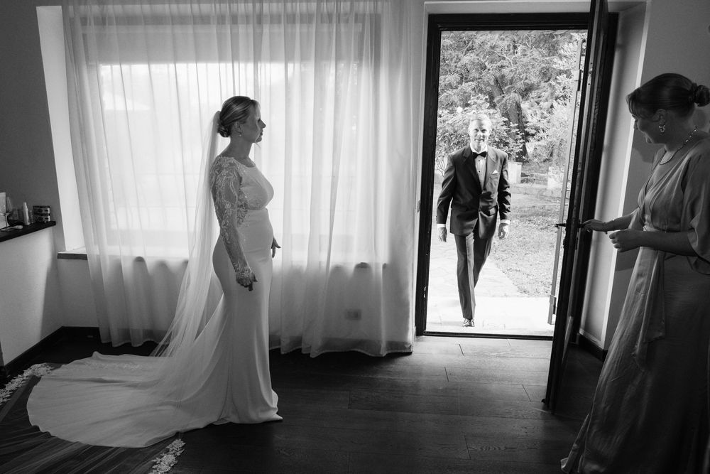 A series of black and white wedding preparation photos showing dress details and silhouettes in window light.