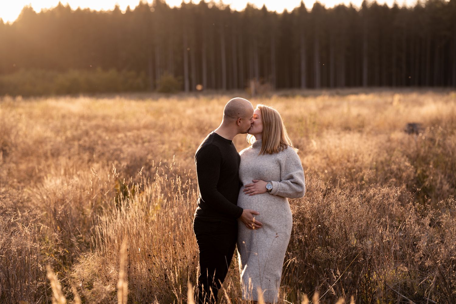 Couple maternity photoshoot on field golden hour