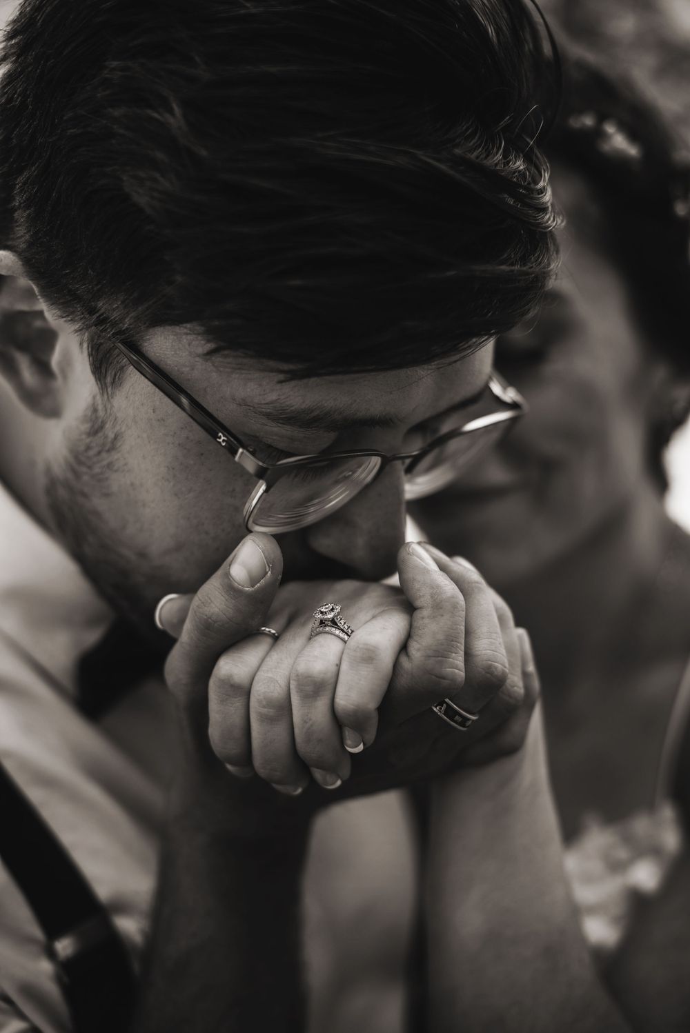 Groom gently kissing bride's hand with engagement ring visible during golden-hour Tahoe engagement session. Couple photography by Alicia.