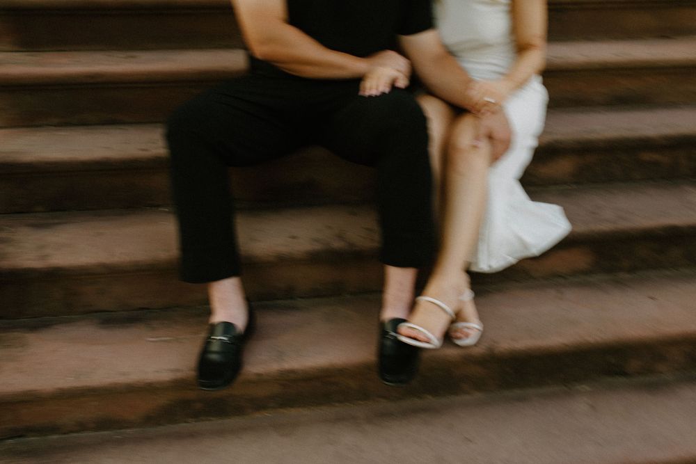 Stylish black shoes and bare legs visible on wooden steps in a moody indoor setting.