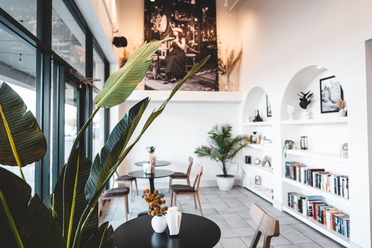 Modern coffee shop interior with wooden ceiling, framed wall art, counter service area and communal table seating.