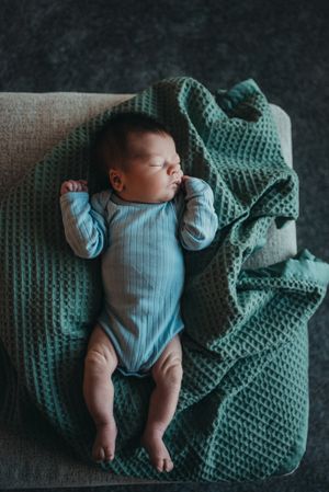 Newborn baby stretched out on sofa during newborn lifestyle session - in-home photography