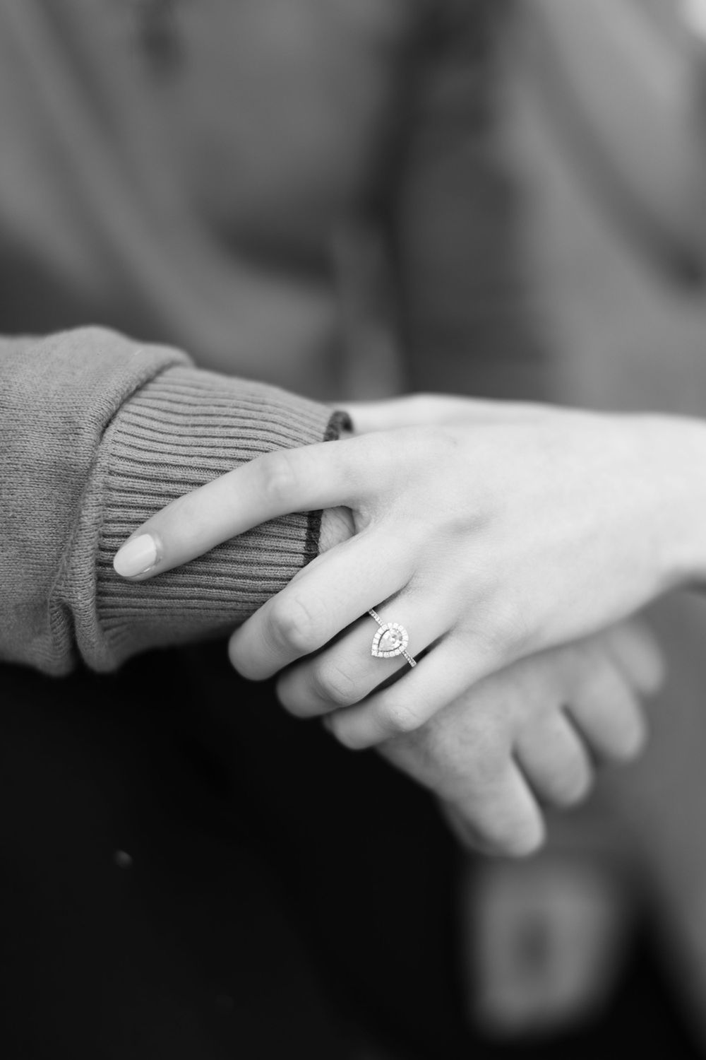 Close-up of hands with diamond engagement ring in black and white.