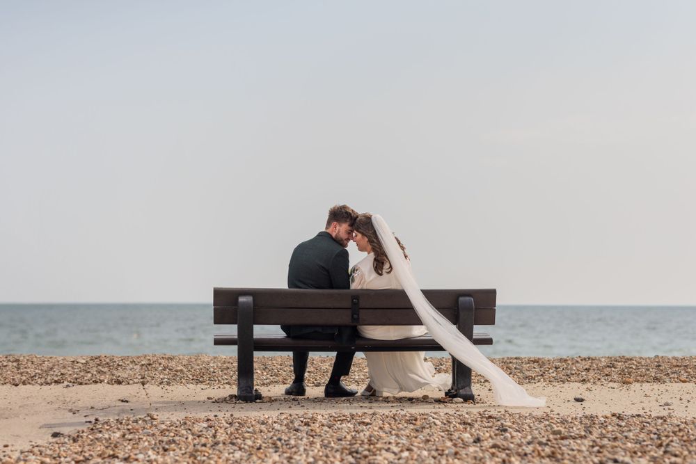 A couple sharing an intimate moment on a wooden bench by the seaside.