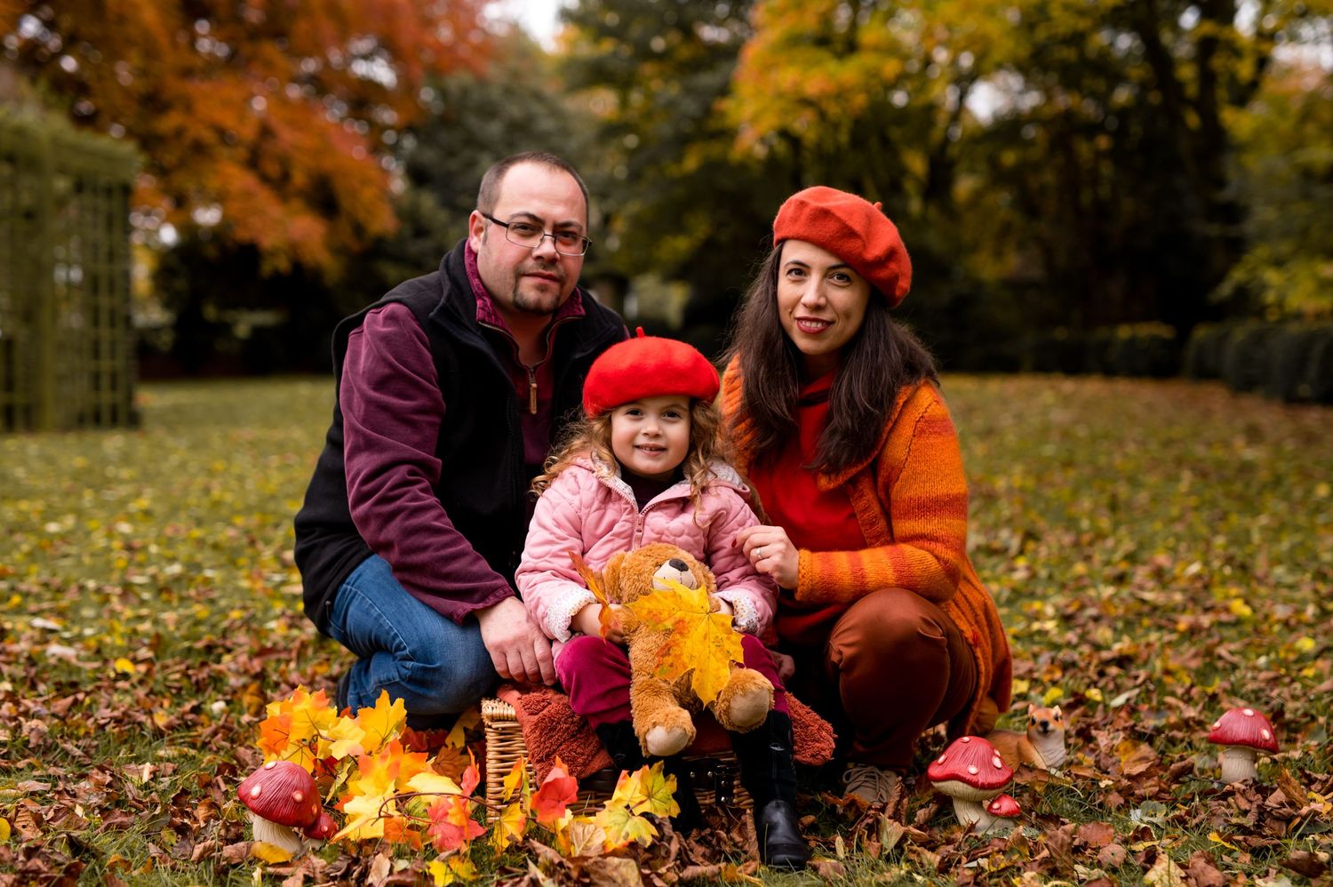 Autumn family portrait with colorful fallen leaves in a park setting.